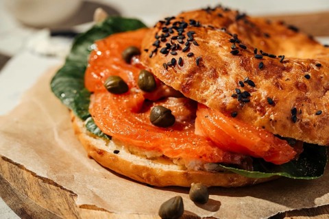 Close-up of a tasty bagel topped with smoked salmon, capers, and fresh greens. Perfect for