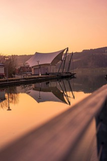 Large tent next to a pier by the lake, quiet atmosphere at dusk and reflection in the water, Großer