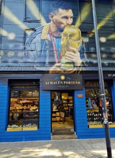 Shop front with a large mural of footballer Lionel Messi with trophy, La Boca neighbourhood, Buenos