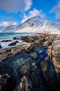 Beach of Norwegian sea on rocky coast in fjord on sunset in winter. Vareid beach, Lofoten islands,