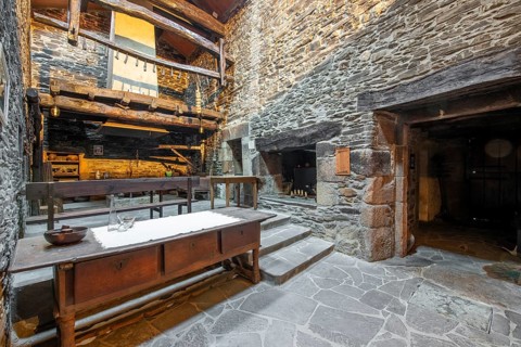 Rustic and traditional interior of a stone country house in Lugo, Spain, featuring a wooden balcony