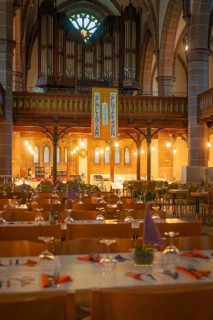 Interior view of a church with organ in the background and laid tables in the foreground,