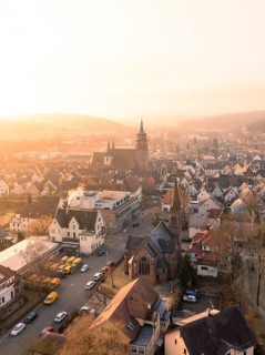 A church and a village in the evening light with a view of hills and trees, Weil der Stadt,