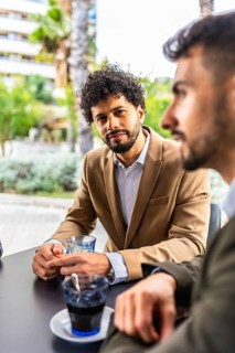 Vertical photo of a businessman listening to colleagues sitting in a cafeteria
