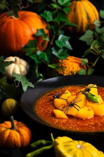 Pumpkin, goulash with artificial spiders and green leaf decorations, autumnal Halloween atmosphere,
