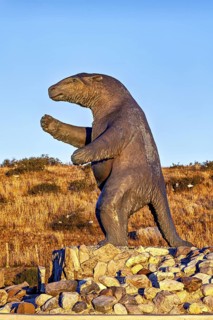 Large sloth statue on a rocky ground in a dry landscape with a clear sky, The statue of the giant