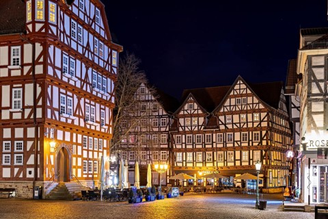 Night scene with illuminated half-timbered houses and a café in a rustic setting, The old town