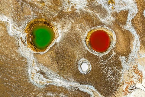 Top view, an aerial drone captures the striking colors of geological ponds within Salar de