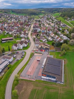 Roads cross a village with a building and neighbouring fields from an aerial perspective,