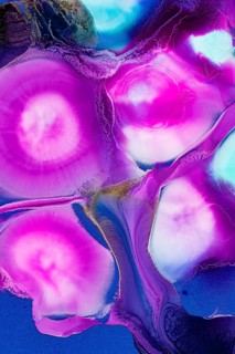 Vibrant pink and blue hues swirl together in this abstract art of ink on a canvas. Rich magenta and