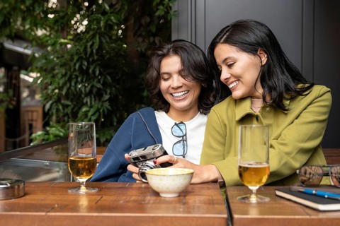 A joyful lesbian couple enjoys a sunny afternoon together, sharing moments with a vintage camera.