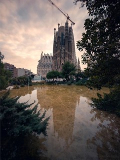 A tranquil scene in Barcelona featuring the iconic Sagrada Familia, its detailed spires reflected
