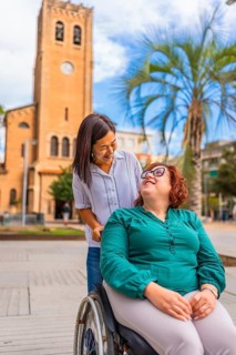 Woman with disability and friend visiting a beauty city walking and pushing the wheelchair downtown