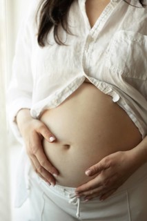 A pregnant woman gently cradles her baby bump, symbolizing the journey of motherhood. She is