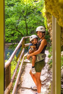 Mother carrying her son in a baby carrier while enjoying a hike through the scenic vintgar gorge