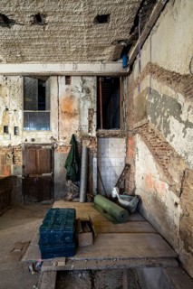 A partially renovated space shows exposed brick, peeling plaster, and construction materials