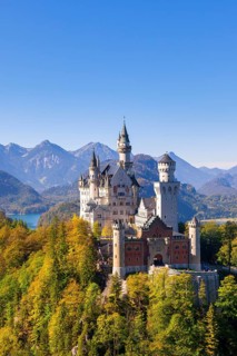 Neuschwanstein Castle surrounded by autumnal forests and mountains in the background, Schwangau,