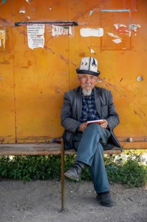 Local man with traditional hat waiting at a bus stop, Issyk-Kul region, Kyrgyzstan