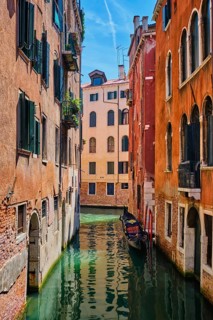Narrow canal between colorful old houses with gondola boat in Venice, Italy