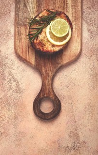 Salmon steak, fried, on a cutting board, top view, rosemary, lemon and lime, homemade, one serving,