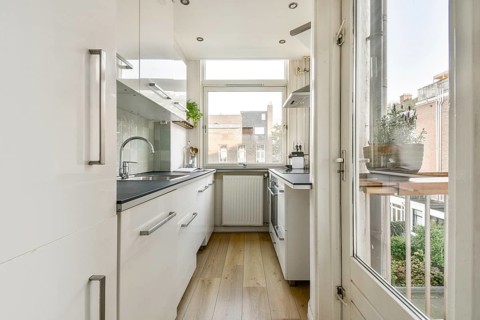 A contemporary kitchen featuring sleek cabinetry, natural light flooding in from large windows, and