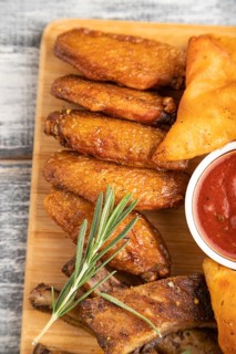 Set of snacks: nachos, chicken wings, fried ribs, bean tortillas on a cutting board on a gray