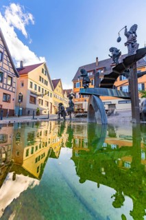 Reflection of traditional houses in a decorative water basin with sculptures under a blue sky, Weil