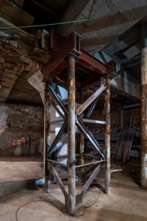 A metal support structure stands firm in a dimly lit construction site. Exposed beams, wooden