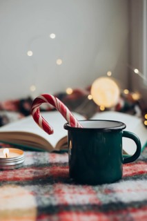 Cozy Christmas setting featuring a steaming mug and a candy cane resting on an open book,