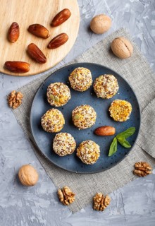 Energy ball cakes with dried apricots, sesame, linen, walnuts and dates with green mint leaves on a