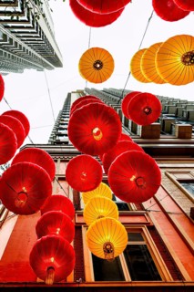 From below radiant red and yellow lanterns hang between skyscrapers in Hong Kong, celebrating