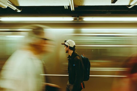 A man pauses in a bustling subway, surrounded by blurred commuters in New York. The scene captures