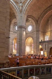Interior view of a church with high walls and visitors in rows of seats, Paris