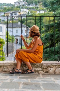 Portrait of a sitting tourist woman looking from a viewpoint at the city of Gjirokaster or