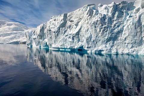 Fascinating iceberg formation with clear reflection in calm water under a blue sky, icebergs in the
