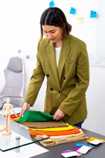 A professional image consultant in an office setting carefully selects vibrant fabrics for a