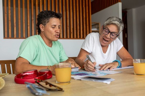A lesbian couple is focused and active as they plan their summer holidays, marking details on