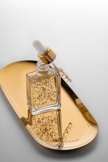 A high-end face serum enriched with gold flakes, presented in a stylish glass bottle with a