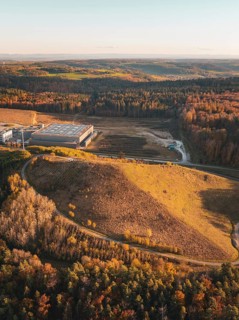 Building complex in an autumnal landscape with colourful forest and rolling hills in the evening