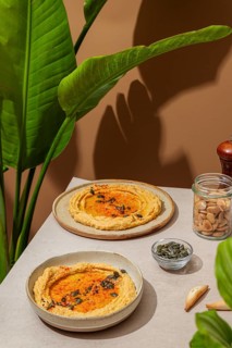 Aesthetic presentation of hummus topped with paprika and seeds, set against a natural background