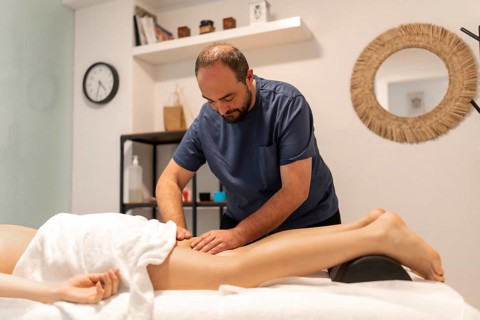 Masseuse working on a client's leg, providing deep tissue therapy for relaxation and muscle