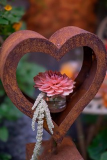 Rusty heart with pink flower in a glass in front of a soft, green backdrop, North Rhine-Westphalia,