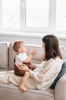 A mother and her son share a tender moment on the couch. The son hands something to the mother,