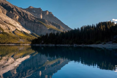 Tranquil lake Oachinensee in Switzerland reflects the majestic surrounding mountains and lush