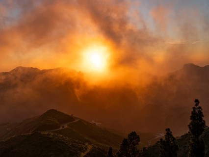Dramatic sunset lighting up the clouds and mist over the mountains, viewed from Cruz de Tejeda in
