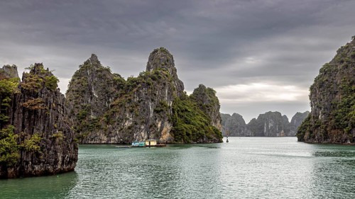 Limestone cliffs and small boats on calm waters under a cloudy sky, The landscape and islands of