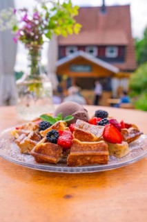 Waffles with berries and ice cream on a table with a café in the background, Cafehäusle Calw, Black