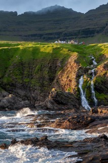 Houses against a mountain backdrop, rocky coast, sea, surf, Vidareidi, Vidoy Island, Viðareiði,