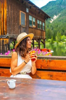 Woman relaxing at lake dobbiaco with a mug, enjoying the mountain landscape in the dolomites