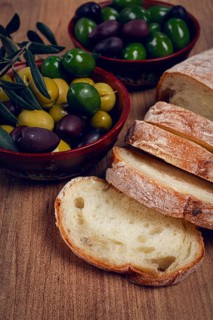A mixture of olives, varieties of Halkidiki, Verdi giganti and Kalamata, in a bowl, with sliced